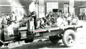 A slain Greenwood Black man on a flatbed moves past neighbors who file into a detention center.